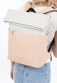 Rucksack aus glattem, hellgrauem und weichem Pfirsichleder, mit einem Roll-Top-Design, einer Reißverschlusstasche und verstellbaren schwarzen Trägern.