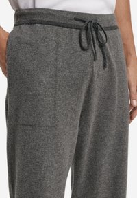 Grå stickade sweatpants med dragsko i midjan, sidosidfickor och mjuk textur. Har ett diskret melerat mönster.