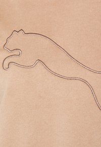Bordo ricamato di una grande felino in salto con filo metallico su sfondo di tessuto beige.