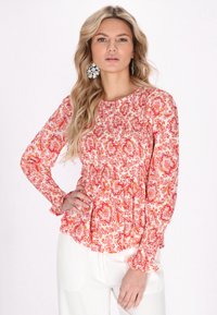 Blusa a maniche lunghe in rosa con stampa paisley, dotata di corpino arricciato, polsini a volant e una vestibilità fluida.