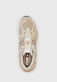 Beige idrettssko med mesh og syntetisk overdel, rund tå, snøring og polstret såle. Har reflekterende detaljer og mønstrede innvendige deler.