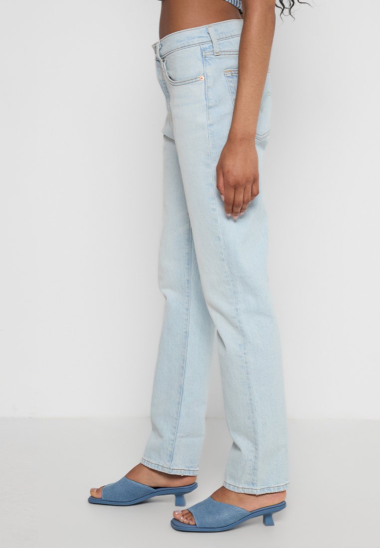 Lichtblauwe spijkerbroek met een rechte pasvorm, voorzien van subtiele vervaging en een klassiek vijf-pocket ontwerp. Draagt een paar blauwe slippers.