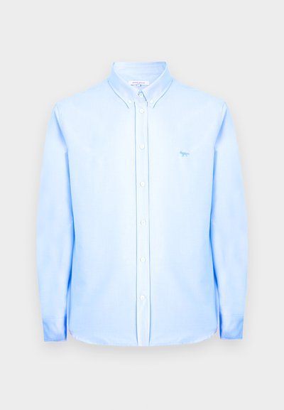 Ανοιχτό μπλε πουκάμισο με μακριά μανίκια, κουμπιά μπροστά και γιακά με κουμπιά, με μικρό λογότυπο αλεπούς στην αριστερή πλευρά του στήθους.