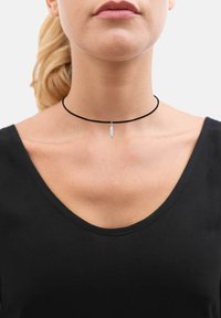 Sorte choker halskæde med en sølvfjer vedh�æng. Bestående af en slank, glat snor og en delikat metallisk detalje.