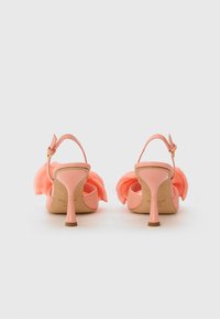Rosa hælhælte sandaler med en bred rem og stoffrynse detalje. Har en slank stilettohæl og ankelrem med en guldspænde.