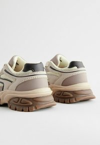 Sneakers med en beige og mauve farveskema, mesh- og syntetiske materialer, teksturerede såler og en polstret ankelkrave.