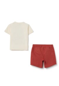 Cotton t-shirt in off-white with short sleeves, paired with red shorts featuring an elastic waistband and side pockets.
