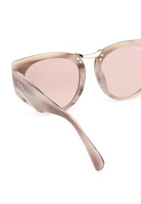 Gafas de sol tipo ojo de gato con un marco translúcido de color marrón claro, lentes rosas y acentos dorados en el puente y las bisagras. Textura suave en todo.