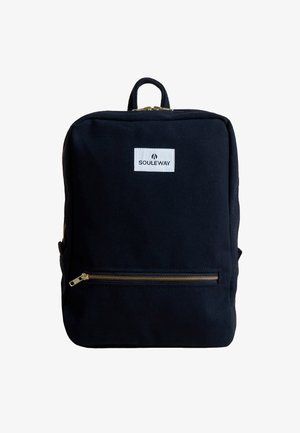 Sac à dos noir en toile avec une forme rectangulaire, accents de fermeture éclair dorés, poche avant et un patch logo blanc. Dispose d'une poignée supérieure.
