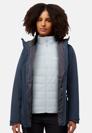 Veste d'extérieur bleu marine, avec une couche intérieure isolante gris clair. Poches zippées, capuche et couleurs contrastées. Texture lisse.