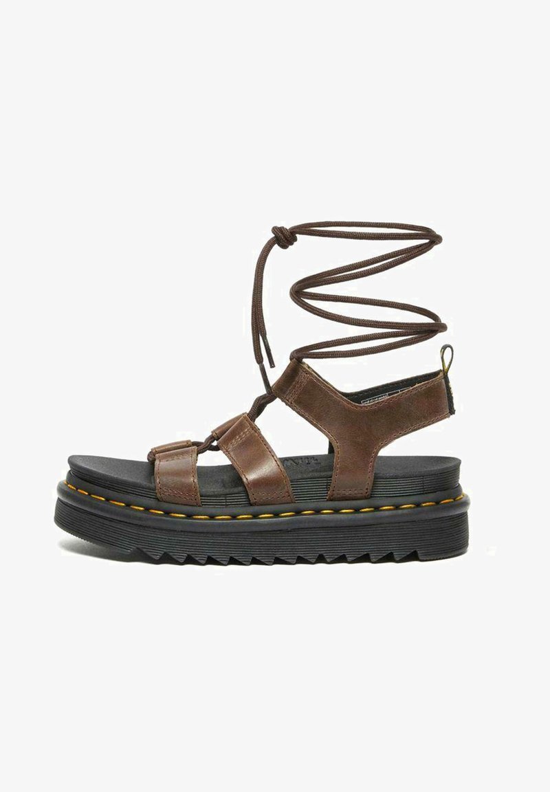 Sandali in pelle marrone con una spessa suola in piattaforma nera, dotati di cinturini incrociati e un design a lacci spirale. Fili gialli accentuano la suola.