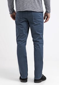 Blauwe katoenen broek met een slim fit, twee achterzakken en een soepele textuur, gecombineerd met zwarte schoenen. Weergave van de achterkant.