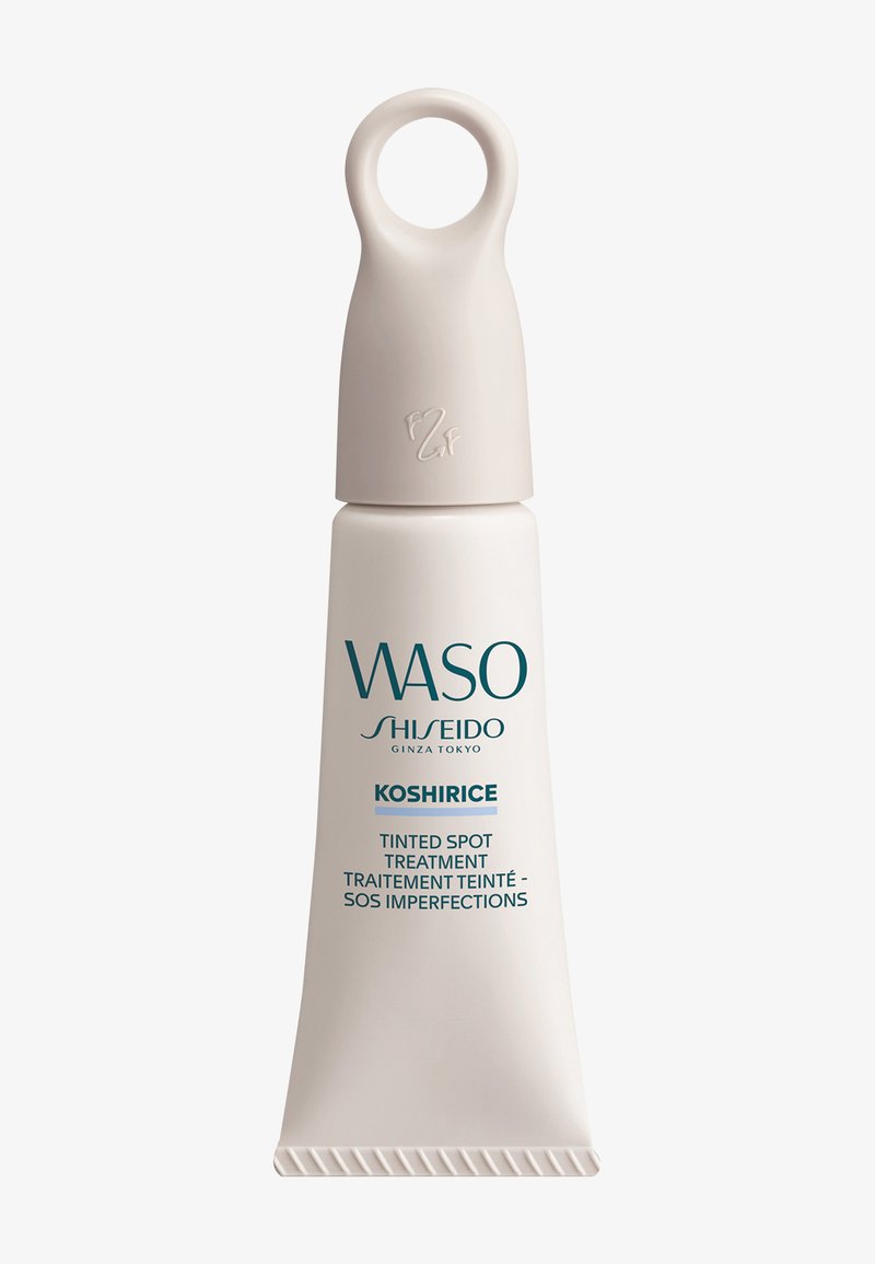 Tube of WASO Shiseido Koshirice tinted spot treatment with beige cap and loop handle on a white background.