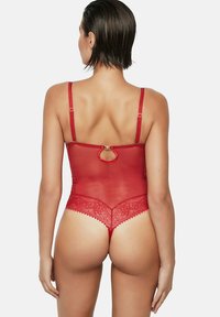 Rode kanten body met doorschijnend mesh, verstelbare bandjes en een open detail aan de achterkant. Kanten rand accentueert de randen.
