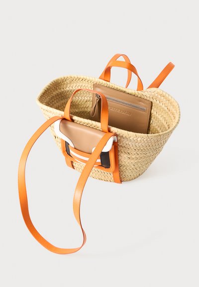 Vævet stråtaske med orange læderstropper, der har en tan læderindvendig lomme med lynlås og kontrasterende hvide detaljer.