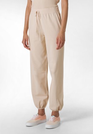 Beige Jogginghosen mit elastischem Bund und Kordelzug. Der Stoff wirkt weich mit gerafften Bündchen. Kombiniert mit Pastell-Sneakern.