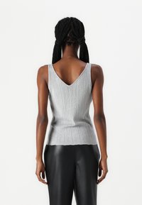 Zilveren geribbelde gebreide tanktop met een V-hals en mouwloze ontwerp, met een gestructureerde afwerking en een geschulpte zoom.