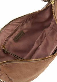 Borsa in suede beige con un interno in rosa liscio, dotata di una tasca con cerniera e un'etichetta del marchio. La chiusura della cerniera è in tonalità dorata.