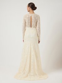 Δαντελένιο φόρεμα με μακριά μανίκια, λουλουδάτες κεντητές λεπτομέρειες σε κρεμ αποχρώσεις, άνοιγμα της πλάτης σε σχήμα κλειδώματος και ρέουσα ουρά. Υφή υφάσματος.