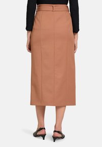 Bruine midi rok met een rechte silhouet, een riem in de taille en twee verticale naden. De stof lijkt gestructureerd en glad.