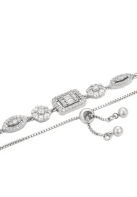 Bracciale in argento con accenti di cristallo a forma di diamante e floreali, dotato di catena regolabile e estremità in metallo lucido su sfondo bianco.