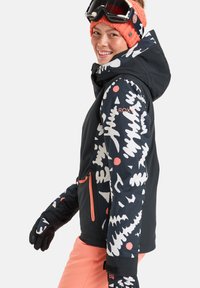 Casaco de neve preto com padrões abstratos em branco e vermelho, detalhes em laranja, bolso com fecho, combinado com calças cor-de-rosa e luvas pretas.