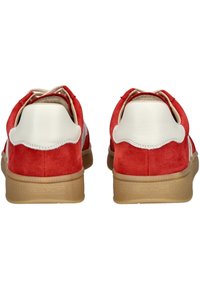 Baskets en daim rouge avec des accents crème, dos arrondi et semelle en caoutchouc beige ; possède un motif texturé et un logo de la marque sur le talon.