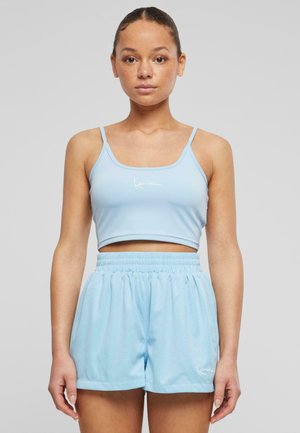 Svijetloplavi atletski crop top s tankim trakama i suptilnim bijelim logotipom, uparen s laganim mrežastim šortsevima u istoj svijetloplavoj boji.
