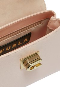 Borsa a tracolla in pelle rosa chiaro con finitura testurizzata, hardware in tonalità oro e una tasca con zip interna. Presenta un'etichetta di marca all'interno.