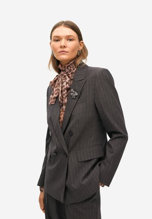 Blazer de rayas grises con diseño de doble botonadura, acompañado de una bufanda de estampado de leopardo marrón y un broche decorativo en la solapa.