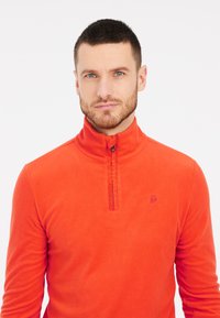 Pullover in pile arancione con mezzo zip, presenta un tessuto testurizzato e un piccolo logo sul petto. Design morbido e leggero.