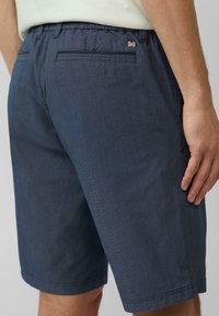 Marineblauwe, gestructureerde shorts met een tailleband met trekkoord, een achterzak met stiksel-details en een metalen logo-accent.