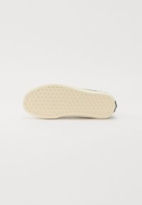 Rubber sneaker sole in cream color with a textured, diamond pattern. Side details include a reinforced heel and a smooth upper edge.