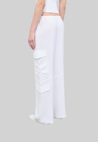 Witte cargo broek met wijde pijpen en elastische tailleband, voorzien van grote zijzakken, subtiele stikdetails en een lichte, gestructureerde stof.