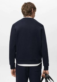 Marineblauwe trui gemaakt van zachte stof, met een ronde hals en geribde manchetten, weergegeven van de achterkant met een eenvoudig ontwerp en geen zichtbare logo's.