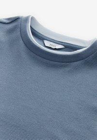 T-shirt bleu à col rond avec des rayures horizontales texturées ; comprend un col intérieur blanc et une étiquette indiquant "NEXT Relaxed Fit".