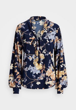 Navy blouse with long puffed sleeves, floral print in beige and light blue, and a tied bow collar.