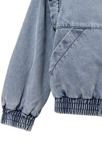 Manica di giacca di jeans azzurro chiaro con polsini arricciati, vita elastica e finitura testurizzata. Presenta dettagli di cucitura diagonale.