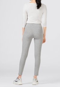 Grå leggings i bomullsblandning, åtsittande silhuett, med en mjuk textur. Parat med vita sneakers för kontrast.