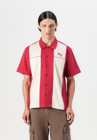 Rød og kremfarget kortermet skjorte med vertikale striper, knapping foran og brodert "Huf"-logo på brystet.