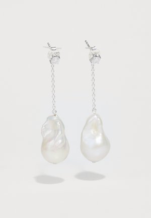 Ehete, millel on ebaregulaarsed pärlitega ripatsi kujundid, koos kettlingi disaini ja kristallist studde accentidega. Värvid on valge ja iridescentne.