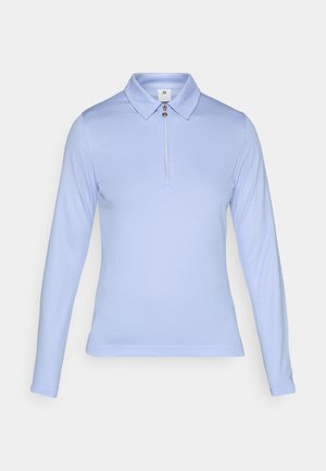 Polo shirt à manches longues bleu clair avec col zippé, tissu texturé et coupe ajustée pour un look épuré.