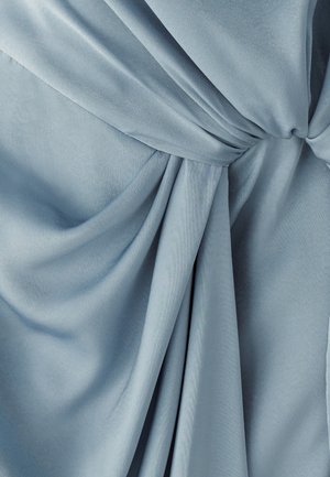 Tessuto azzurro chiaro, setoso con una texture morbida; presenta drappeggi e pieghe sottili, annodato al centro, creando un aspetto a strati.