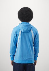 Blaues Kapuzen-Sweatshirt mit strukturiertem Design, mit gerippten Akzenten und weißen Streifen entlang der Schultern. Weiche Stoffoberfläche.