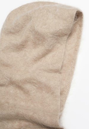Beige knitted shawl made from soft, fluffy material. Features a light texture and slightly woven pattern with uneven edges.
