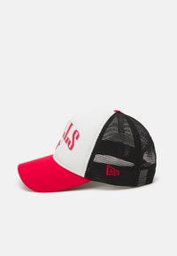 Gorra de camionero con una parte delantera blanca, visera roja y parte trasera de malla negra. Presenta letras rojas en negrita en la parte delantera y un acento de logo en el costado.