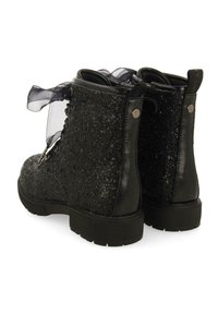 Stivaletti neri presentano una texture glitterata, una finitura in pelle liscia, dettagli in raso e una suola spessa per maggiore stabilità.