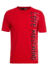 Červené bavlněné tričko s vertikálním černým potiskem, který na levé straně nápis "LOVE MOSCHINO". Klasický kulatý výstřih.