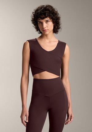 Oben: brauner ärmelloser Crop-Top mit V-Ausschnitt und überkreuzter Vorderseite. Unten: hochgeschnittene braune Leggings. Glatter, dehnbarer Stoff.