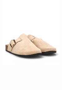 Zapatos slip-on de ante beige con suela de corcho, que presentan una hebilla metálica lateral y un diseño suave y curvado. Perfil plano con una textura suave.